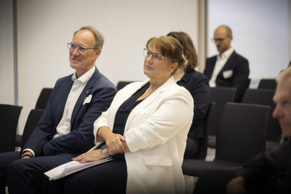 Eine Frau und ein Mann sitzen im Publikum und hören dem Bühnenprogramm interessiert zu.